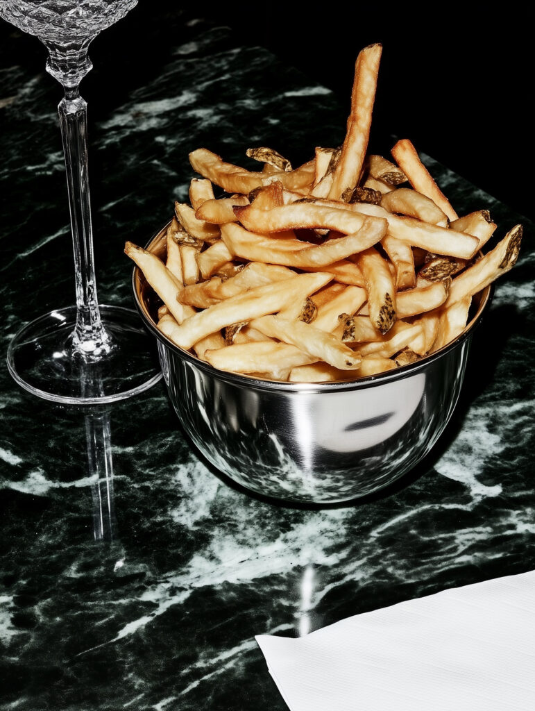 french fries in a stainless steel bowl on a black marble table